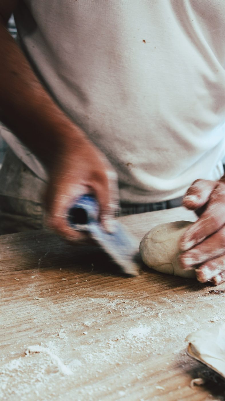 Mains du boulanger coupant la pâte au coupe-pâte